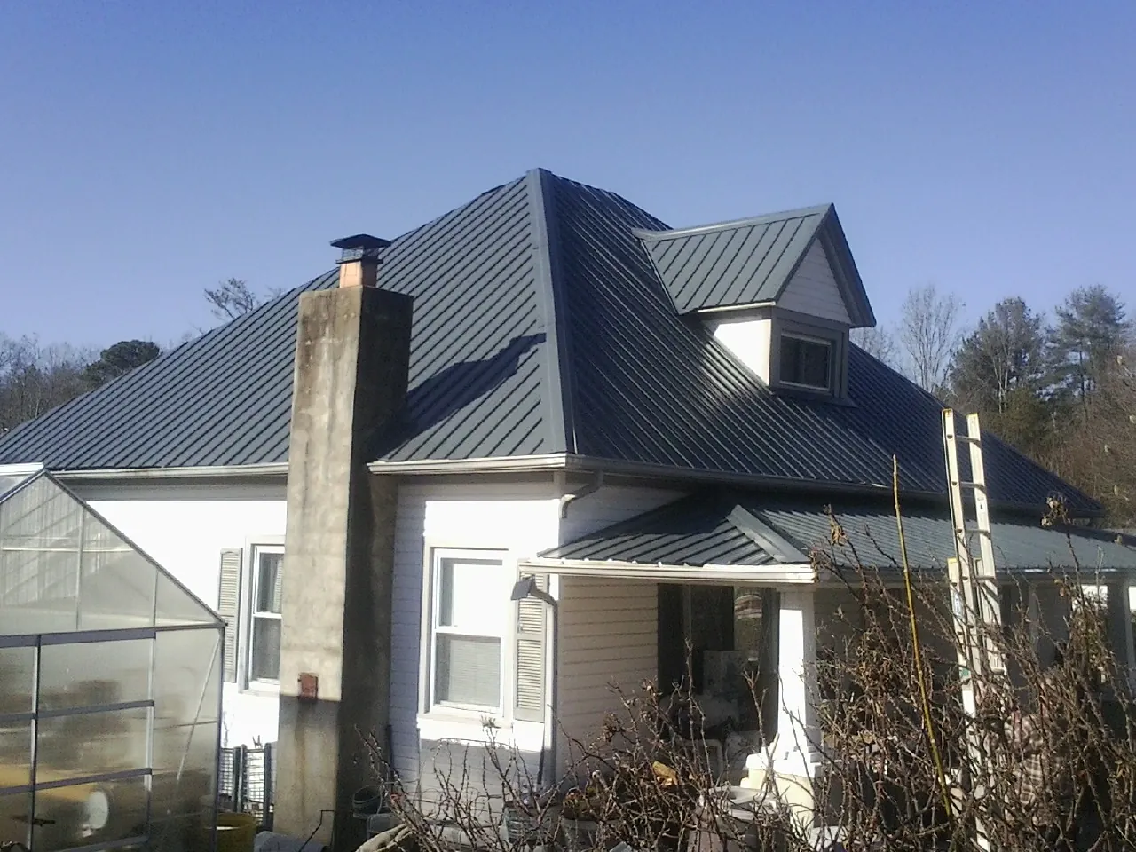 Dark blue standing seam metal roof on a white farmhouse with dormer — Slate & Tile Roof Repair by Roofing Brothers in Bloomingburg