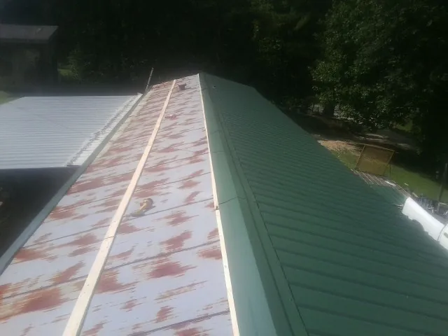 Old rusted panels beside newly installed green metal roofing — Wind Damage Roof Repair by Roofing Brothers in Bloomingburg